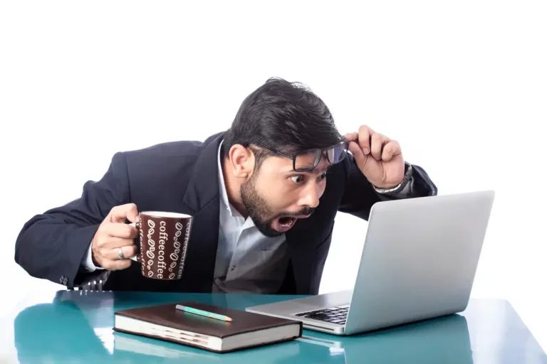 surprised or astonished businessman looking at laptop while drinking coffee in isolated background