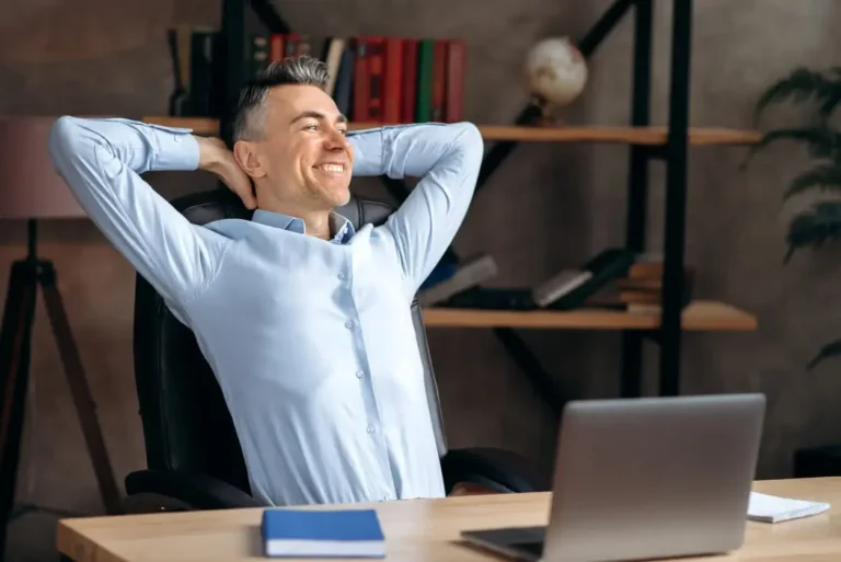 Satisfied self-confident caucasian businessman, lawyer or office employee, relaxes at the workplace and smiles, sits in a modern office, rests from work, dreams of a vacation, looks away